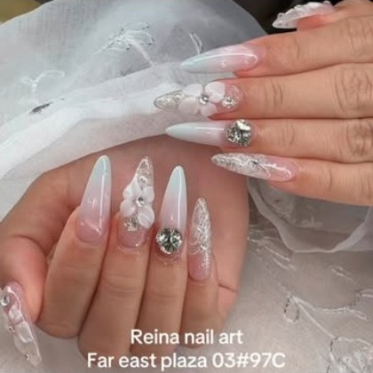 Ombre stiletto nails with sculpted white flowers and a crystal, on sheer white fabric