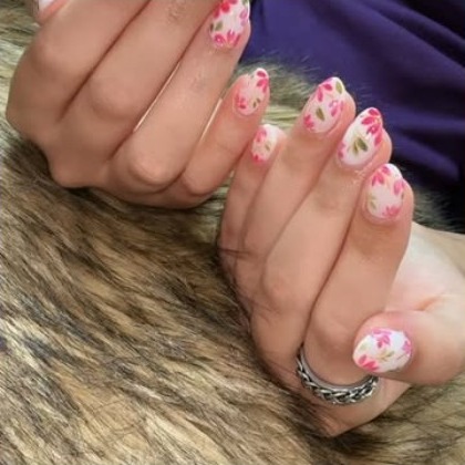 Hand with pink and white floral nail art and a silver ring