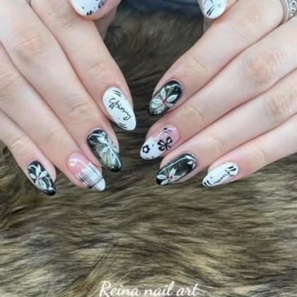 Nails painted with black and white botanical line art across a translucent milk base